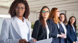 Confident African American woman with paper documents. Professional business team standing in row. Business concept