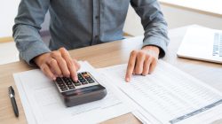Close-up of unrecognizable man working with financial data. He using calculator and examining document. Financial inspector holding examination. Paperwork or finance concept